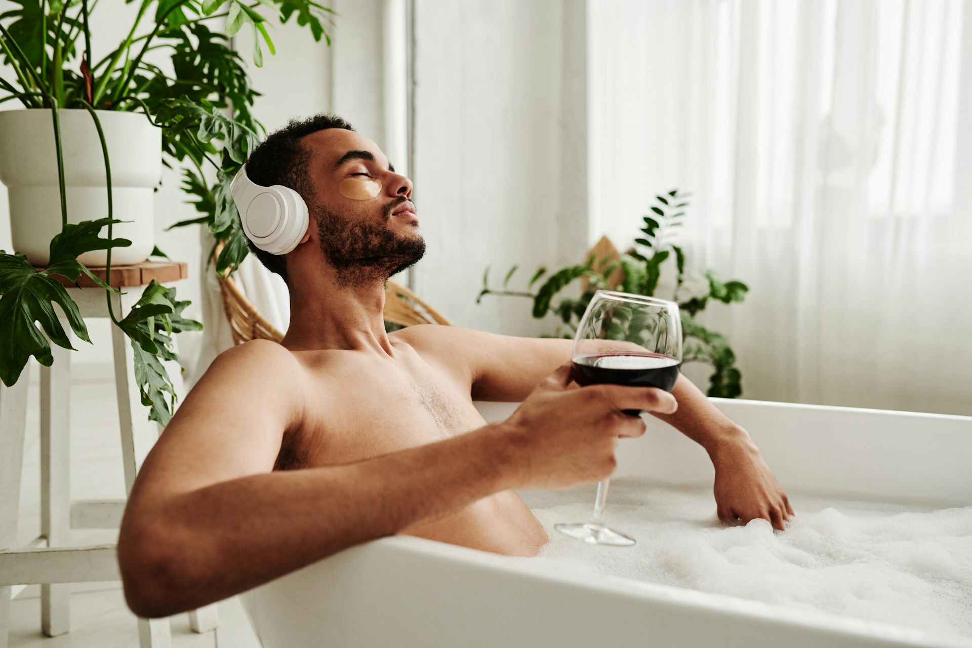 Man relaxing in a bath with a glass of wine